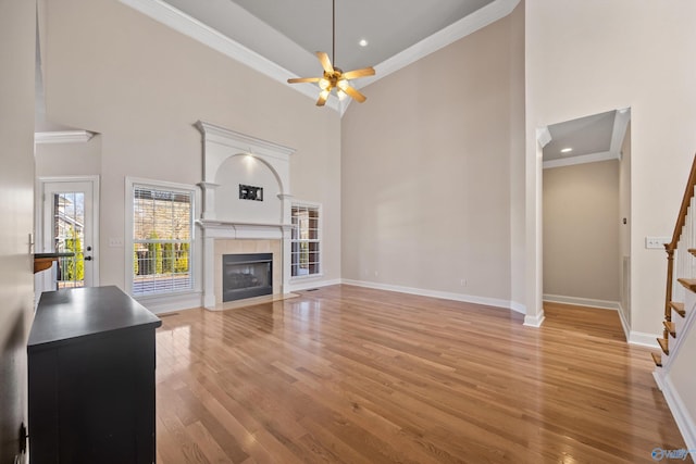 unfurnished living room with stairway, light wood-type flooring, a fireplace, and crown molding