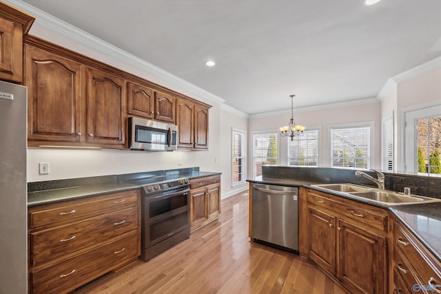 kitchen featuring dark countertops, light wood-style floors, stainless steel appliances, and a sink