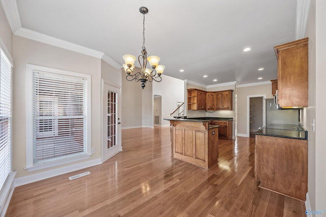 kitchen featuring brown cabinets, a notable chandelier, dark countertops, visible vents, and wood finished floors