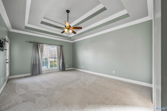 unfurnished room with a raised ceiling, light colored carpet, and baseboards