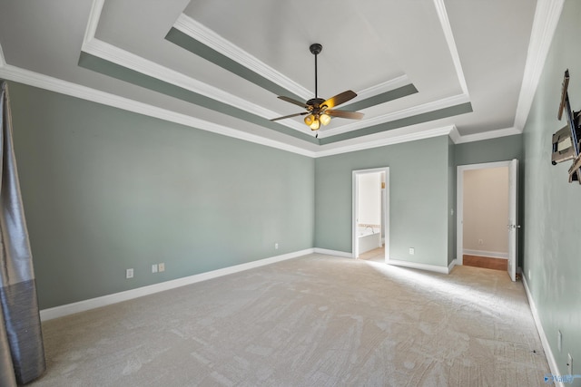 unfurnished bedroom featuring ornamental molding, a tray ceiling, light colored carpet, and baseboards