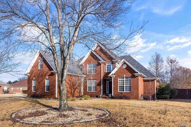 traditional home with a front yard, fence, and brick siding