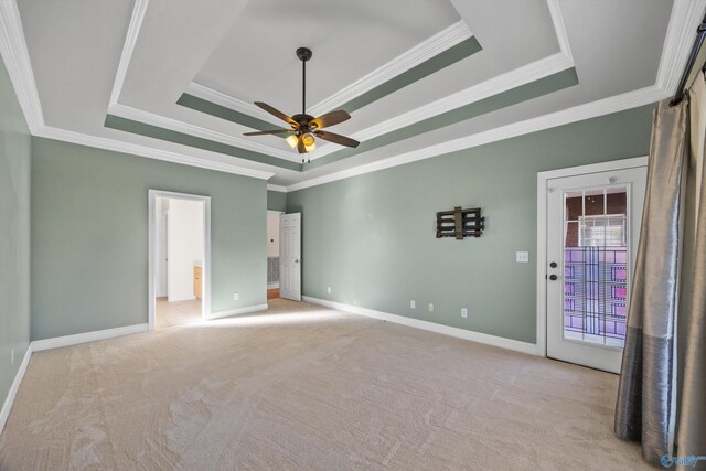 unfurnished bedroom with baseboards, a tray ceiling, and light colored carpet