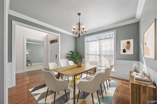 dining space with a chandelier, wainscoting, wood finished floors, and crown molding