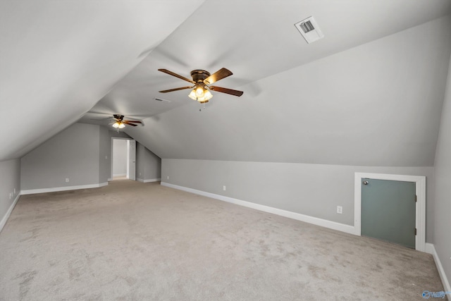 additional living space featuring light colored carpet, vaulted ceiling, visible vents, and baseboards