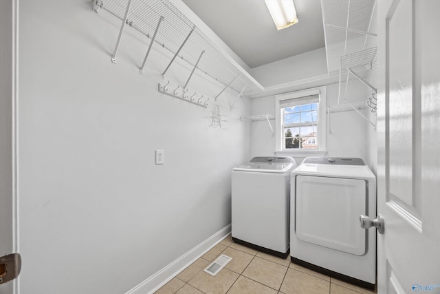 clothes washing area featuring light tile patterned flooring, laundry area, separate washer and dryer, visible vents, and baseboards