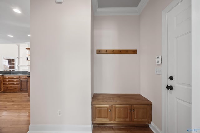 mudroom with crown molding, baseboards, and wood finished floors