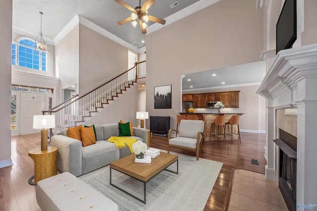 living room featuring a fireplace, stairway, ornamental molding, light wood-type flooring, and baseboards