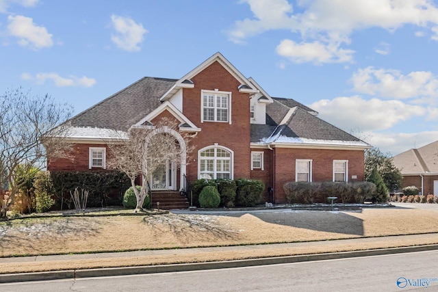 traditional-style house with a shingled roof and brick siding