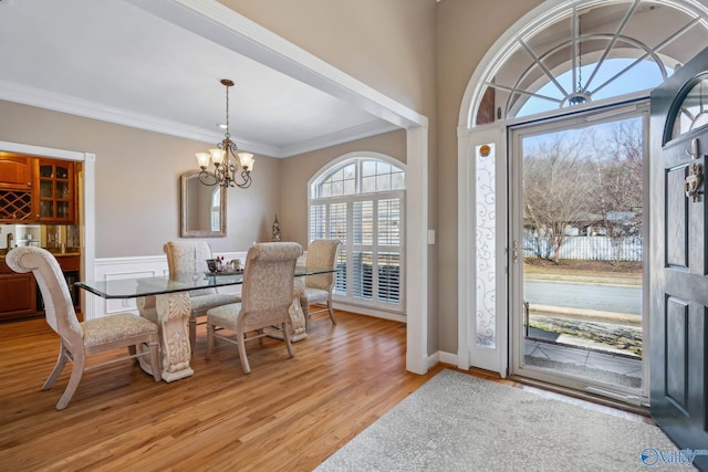 dining room with a chandelier, light wood finished floors, and ornamental molding