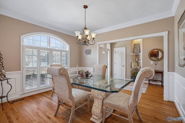 dining area featuring a chandelier, a wainscoted wall, and light wood finished floors