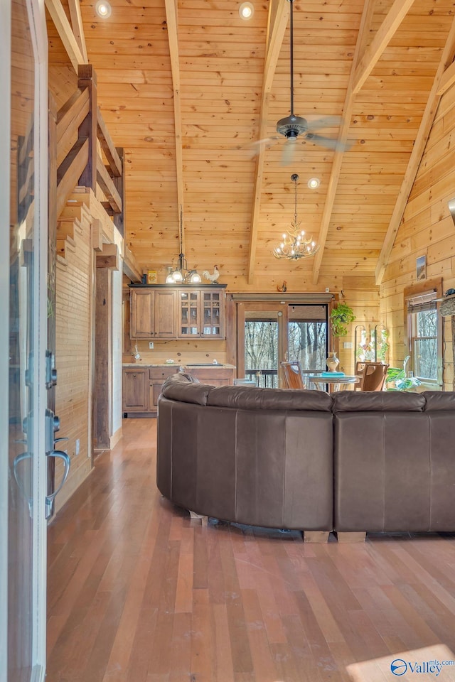 unfurnished living room featuring beamed ceiling, wood walls, and light wood-type flooring