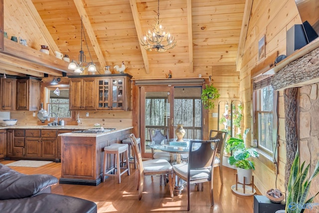 kitchen featuring light countertops, a sink, wood walls, and brown cabinets