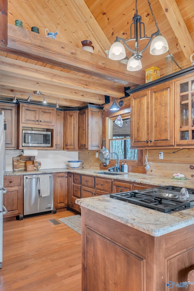 kitchen with beamed ceiling, brown cabinets, appliances with stainless steel finishes, a sink, and wooden ceiling