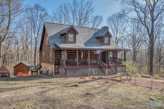 log cabin featuring a chimney, a shingled roof, central AC, and a porch