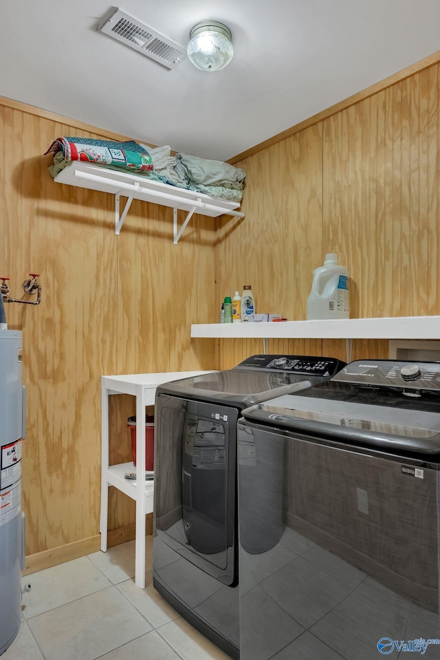 laundry area with water heater, washing machine and dryer, laundry area, light tile patterned floors, and visible vents