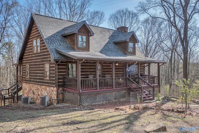 cabin featuring stone siding, a chimney, central AC, and a shingled roof