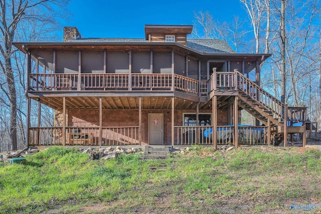 back of property featuring a sunroom, stairway, roof with shingles, and a wooden deck