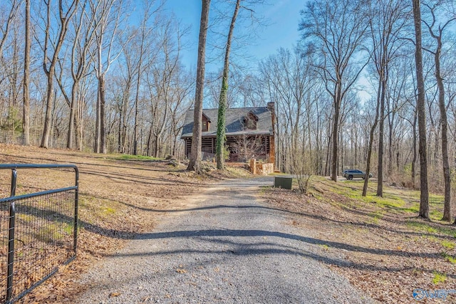 exterior space featuring driveway, a shingled roof, fence, and a chimney
