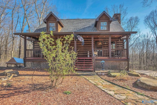 rear view of house featuring a porch, a shingled roof, and a chimney
