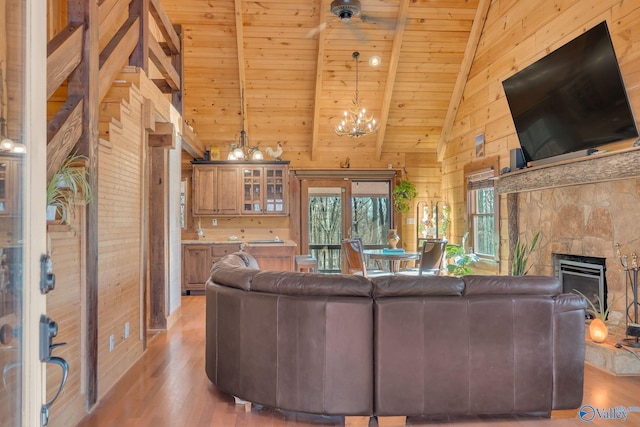 living area with a notable chandelier, high vaulted ceiling, wooden ceiling, wood walls, and light wood-type flooring