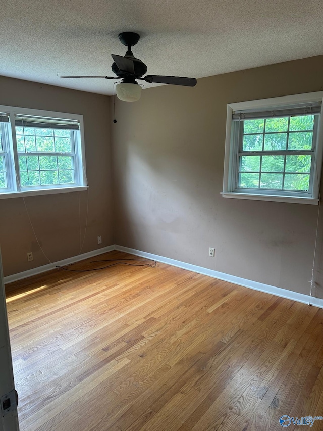 unfurnished room with baseboards, a ceiling fan, a textured ceiling, and light wood-style flooring