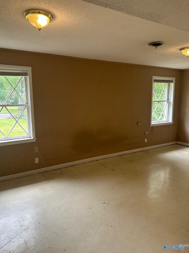 unfurnished room with tile patterned floors, baseboards, a textured ceiling, and visible vents
