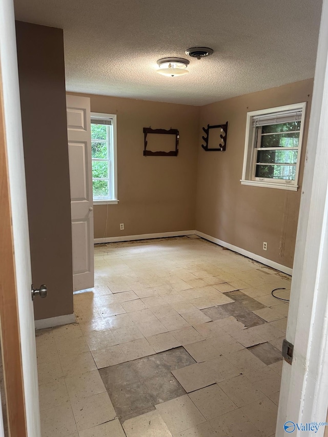 unfurnished room featuring a textured ceiling and baseboards