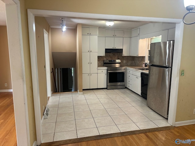 kitchen with decorative backsplash, baseboards, under cabinet range hood, a sink, and appliances with stainless steel finishes