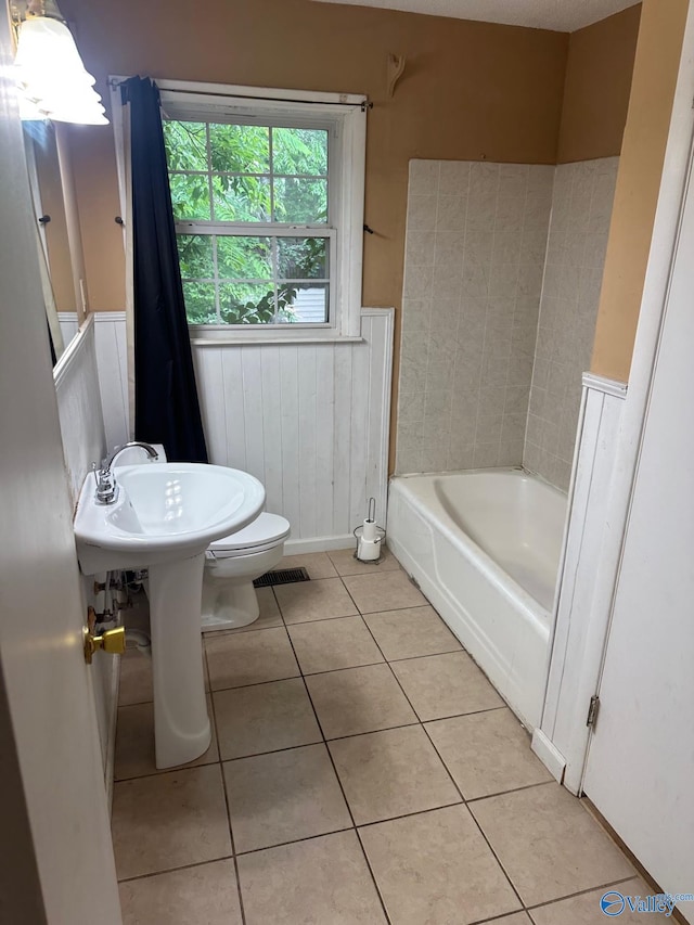 full bathroom with visible vents, toilet, a washtub, tile patterned floors, and a wainscoted wall