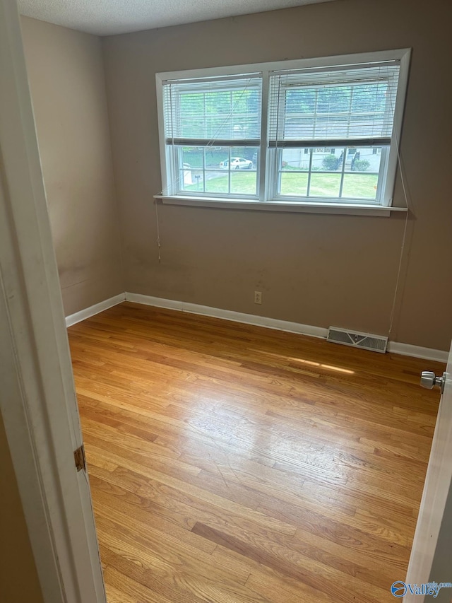 spare room with baseboards, light wood-style flooring, and visible vents