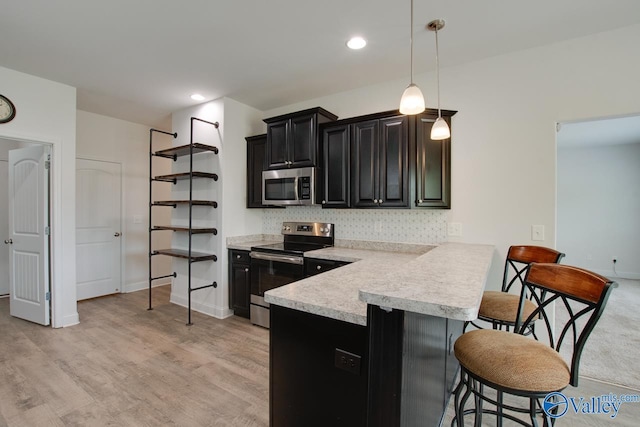 214 Tybee Dr, Madison, AL 35756 - kitchen featuring a peninsula, a kitchen breakfast bar, light countertops, dark cabinetry, and appliances with stainless steel finishes