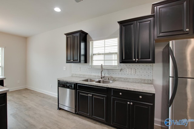 214 Tybee Dr, Madison, AL 35756 - kitchen featuring appliances with stainless steel finishes, a sink, light wood-style floors, light countertops, and backsplash