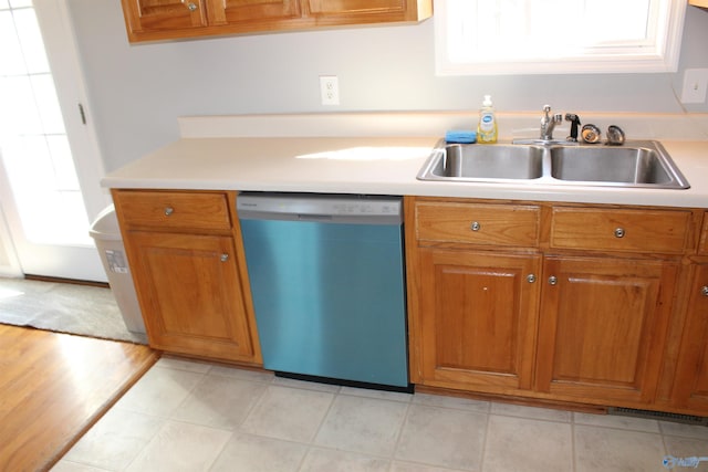 kitchen featuring dishwasher, light countertops, a sink, and brown cabinets