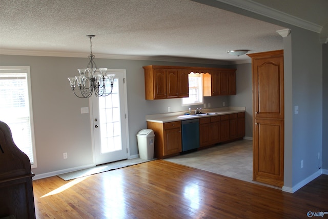 kitchen with crown molding, light countertops, light wood-style floors, a sink, and dishwashing machine