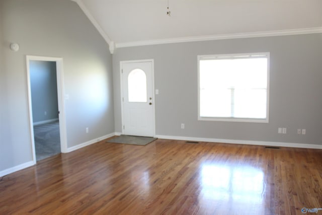 foyer featuring lofted ceiling, ornamental molding, wood finished floors, and a wealth of natural light