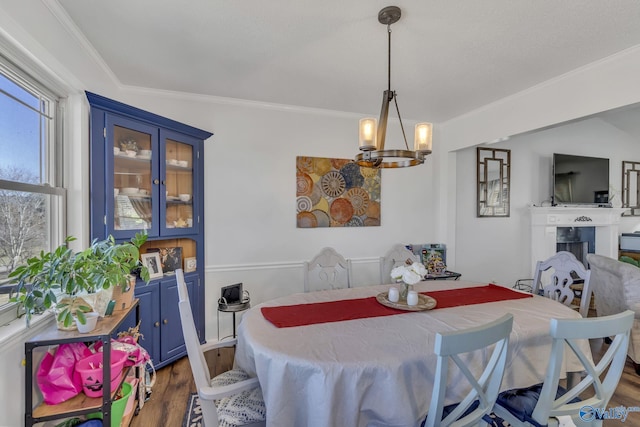 dining room with dark wood-type flooring, ornamental molding, and an inviting chandelier