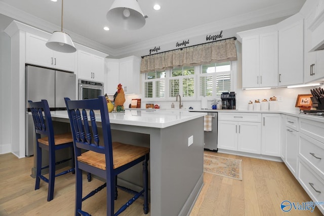 kitchen featuring white cabinetry, stainless steel appliances, a breakfast bar area, and light hardwood / wood-style flooring