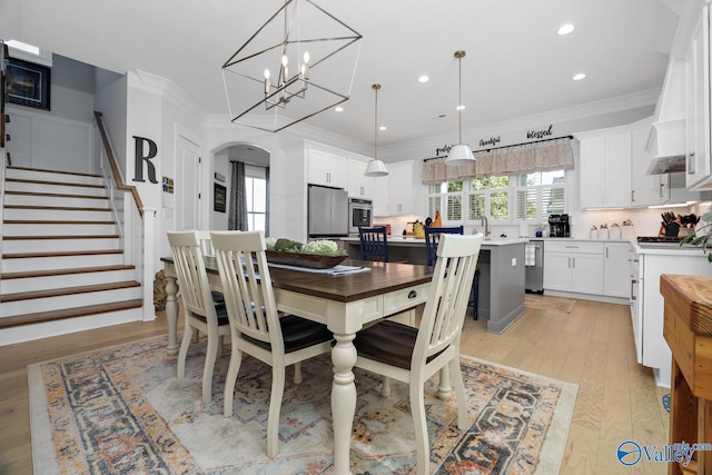 dining space featuring light hardwood / wood-style flooring, crown molding, and an inviting chandelier