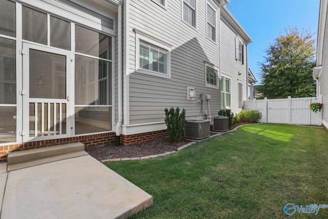 view of side of home with a yard, a sunroom, and central air condition unit