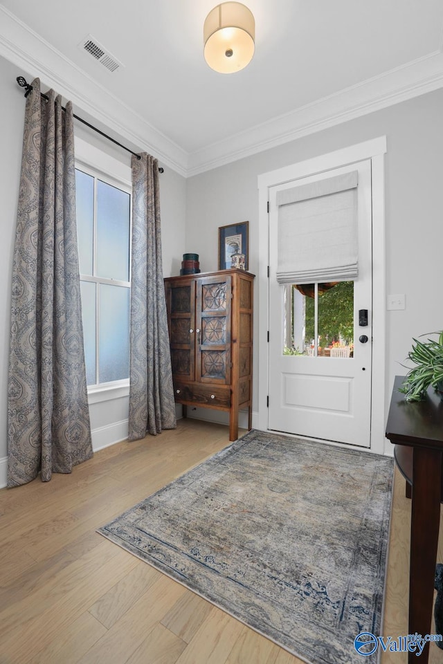 foyer featuring a healthy amount of sunlight, ornamental molding, and hardwood / wood-style flooring