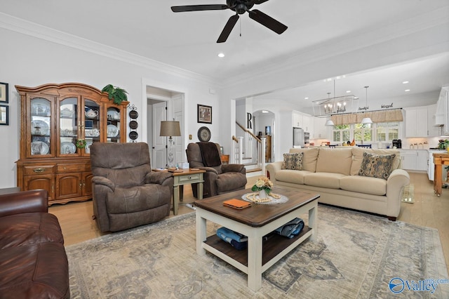 living room with light hardwood / wood-style floors, ceiling fan with notable chandelier, and ornamental molding