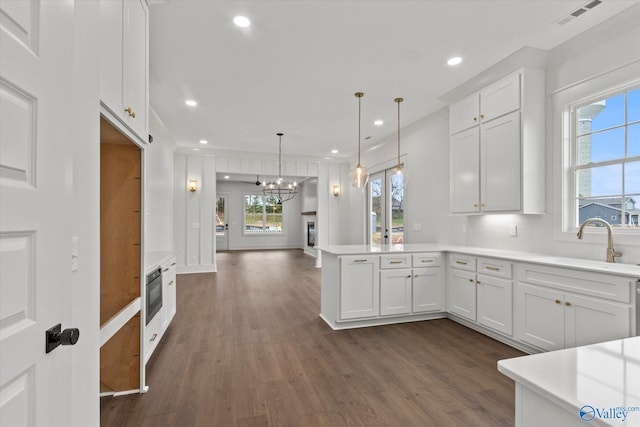 kitchen featuring plenty of natural light, white cabinetry, and hanging light fixtures