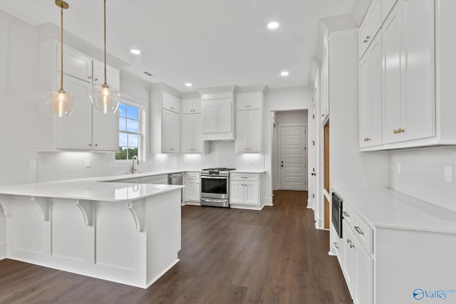 kitchen featuring white cabinets, stainless steel gas stove, kitchen peninsula, and decorative light fixtures