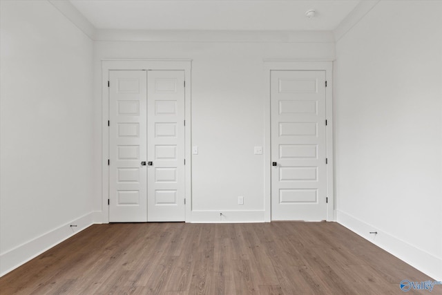 unfurnished bedroom featuring ornamental molding, a closet, and hardwood / wood-style floors