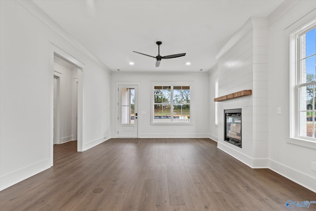 unfurnished living room featuring a fireplace, dark hardwood / wood-style floors, ceiling fan, and a wealth of natural light