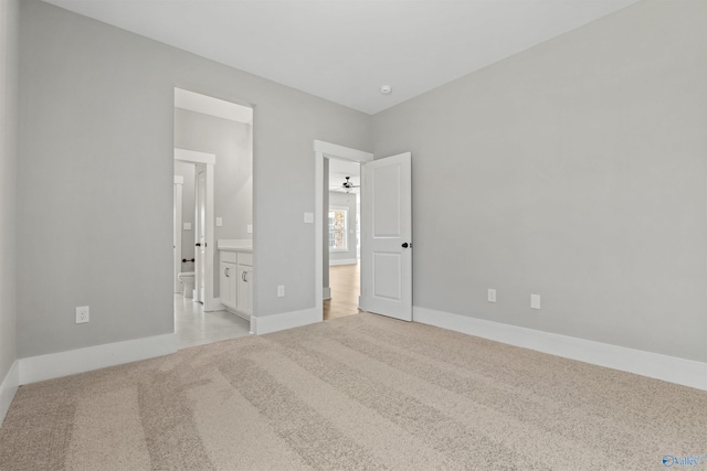 unfurnished bedroom with light carpet, baseboards, and connected bathroom