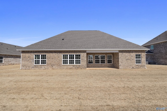 back of property with roof with shingles and brick siding