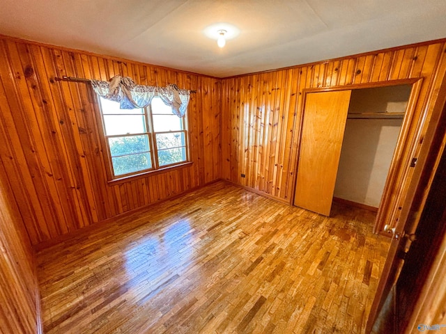 unfurnished bedroom featuring wood walls, a closet, and hardwood / wood-style flooring