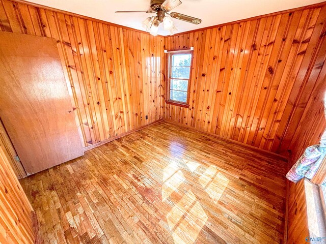 spare room with hardwood / wood-style flooring and wooden walls